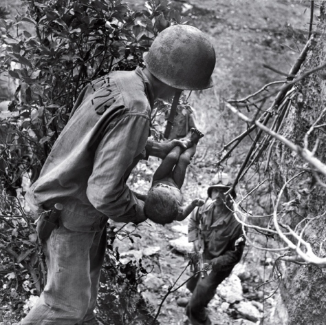 In a photo that somehow comprises both tenderness and horror, an American Marine cradles a near-dead infant pulled from under a rock while troops cleared Japanese fighters and civilians from caves on Saipan in the summer of 1944. The child was the only person found alive among hundreds of corpses in one cave.